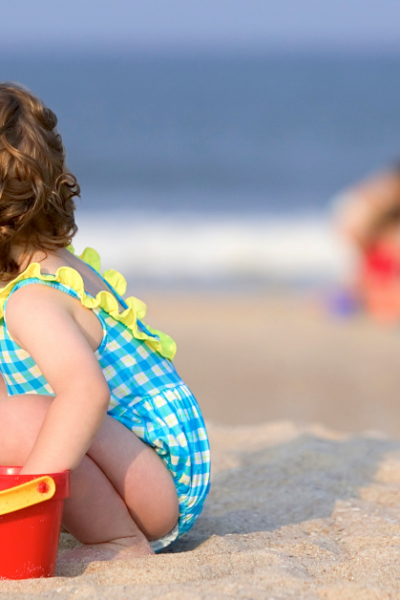A toddler playing in the sand with beach essentials for toddlers