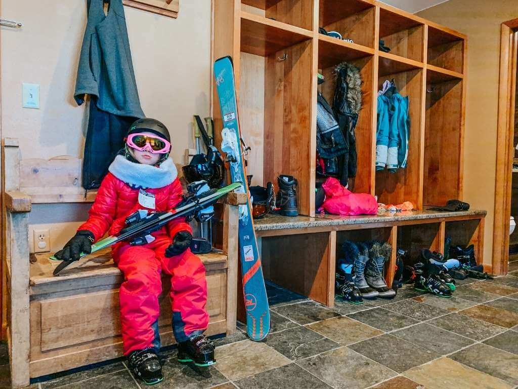 girl sitting with all her ski gear ski trip packing list